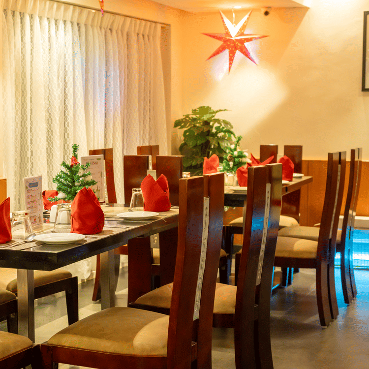 Image of restaurant minimally decorated for Christmas with mini Christmas trees placed on each table