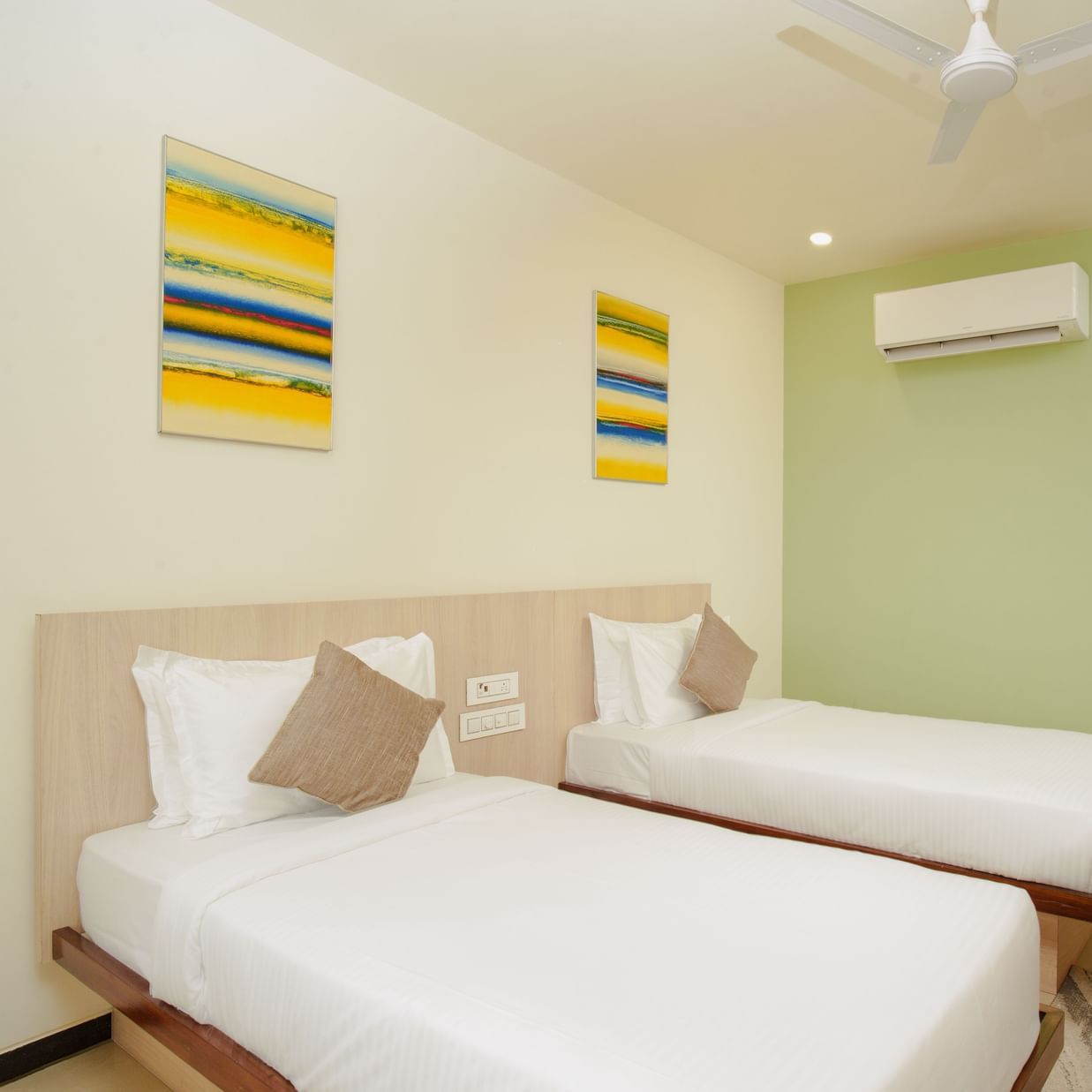 Hotel room interior with three beds and an air conditioning unit at Arawali Ananta Elite, Jaipur.