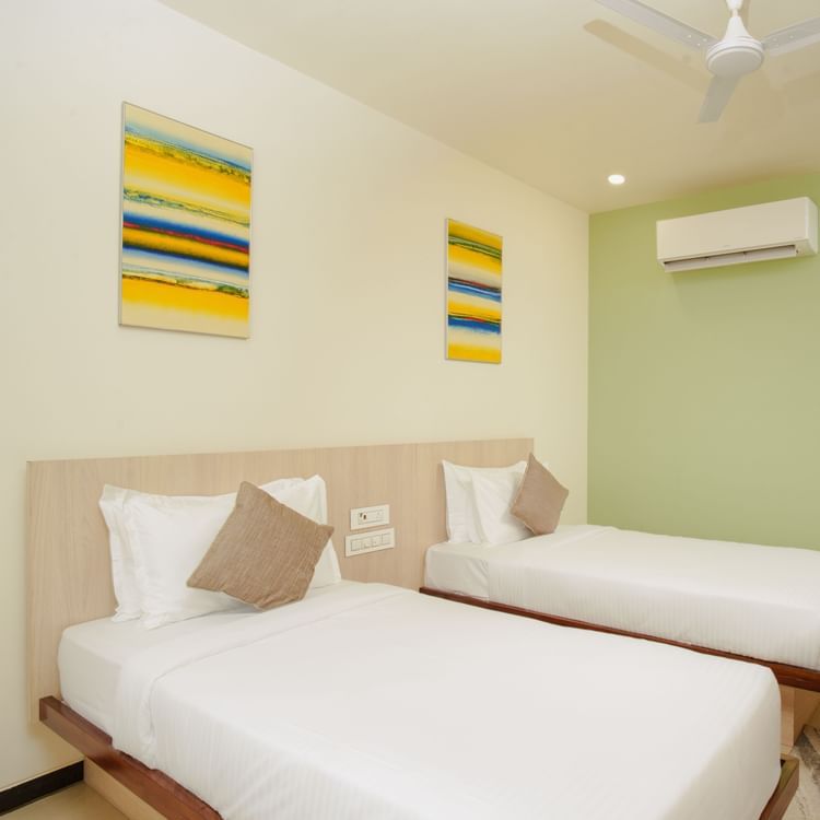 Hotel room interior with three beds and an air conditioning unit at Arawali Ananta Elite, Jaipur.