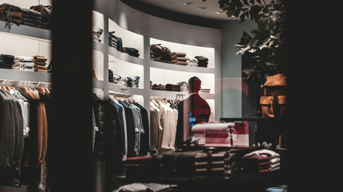 A clothing store interior with racks of garments and a person browsing.