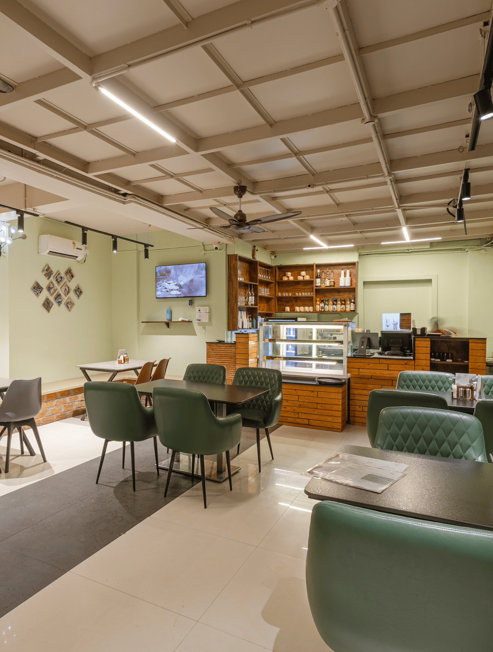 Indoor dining area of Claysutra Pottery Studio And Cafe at Kove Smart Stays that is furnished with multiple dining tables, a display case, and ample lighting.