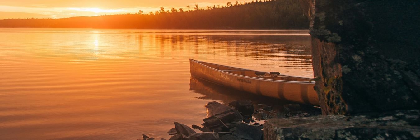 Golden sunset reflecting on calm lake waters with stone structure creating serene evening atmosphere