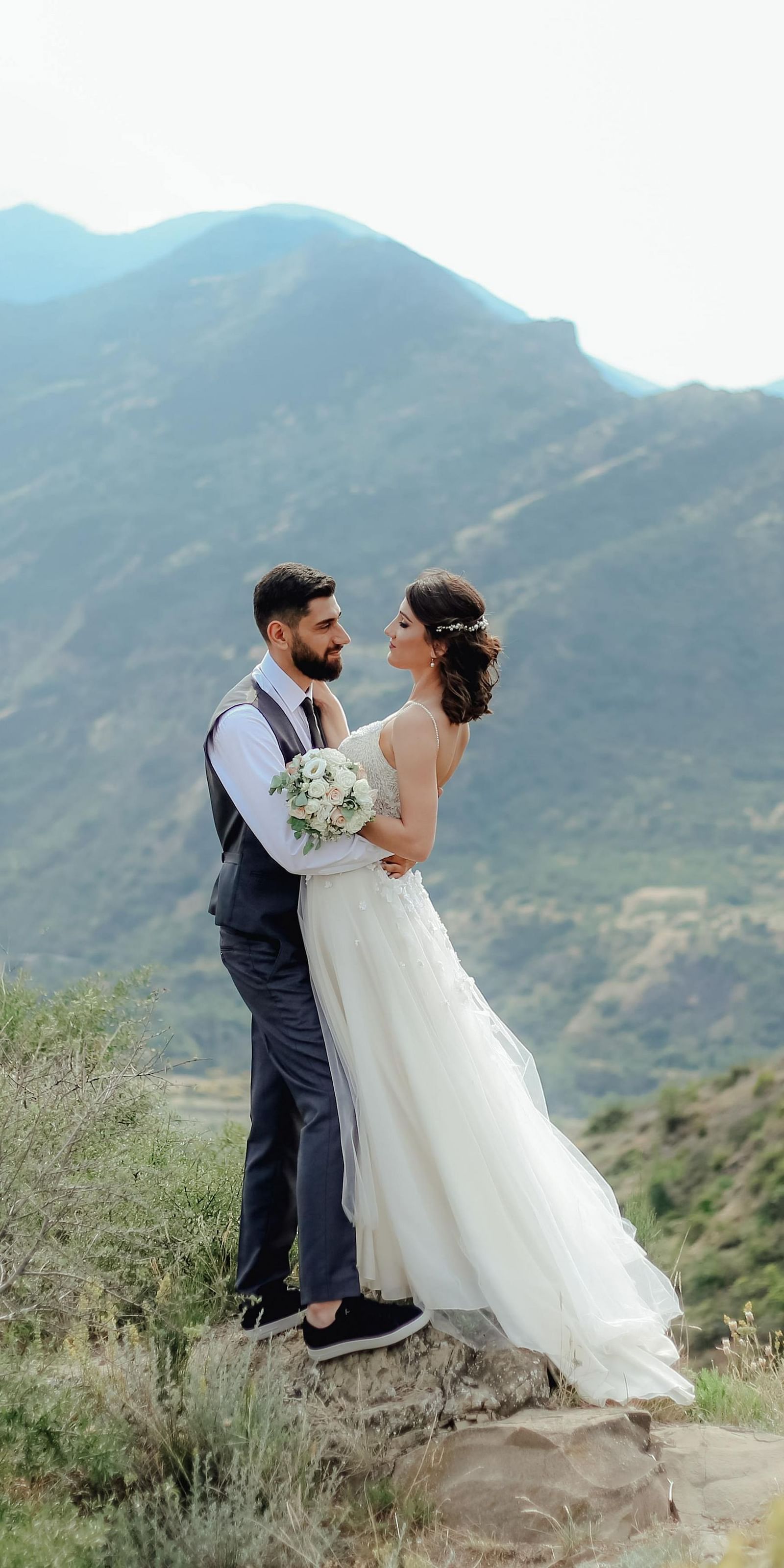 a couple posing for a photograph in western wedding attire in the moutains