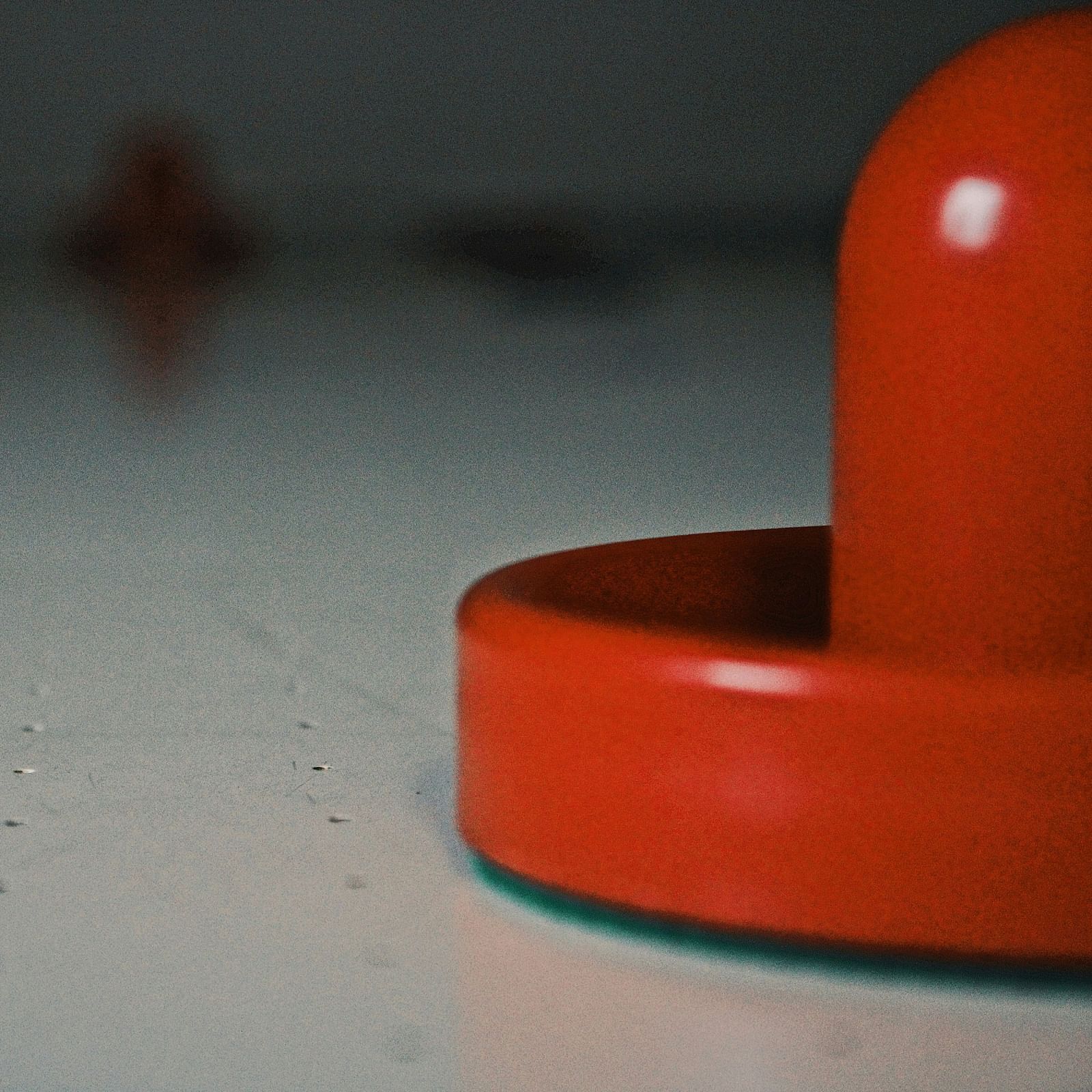 A red air hockey puck on a table.