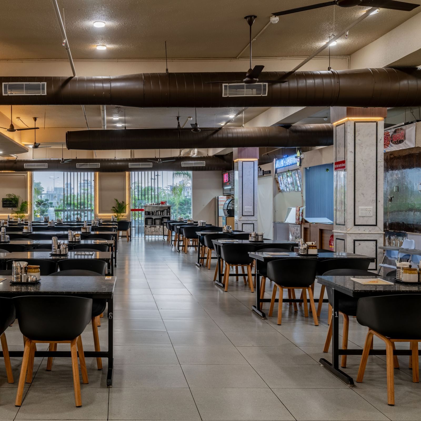 Stylish dining hall with wooden chairs under warm ceiling lighting at Hotel Highway King, Neemrana.