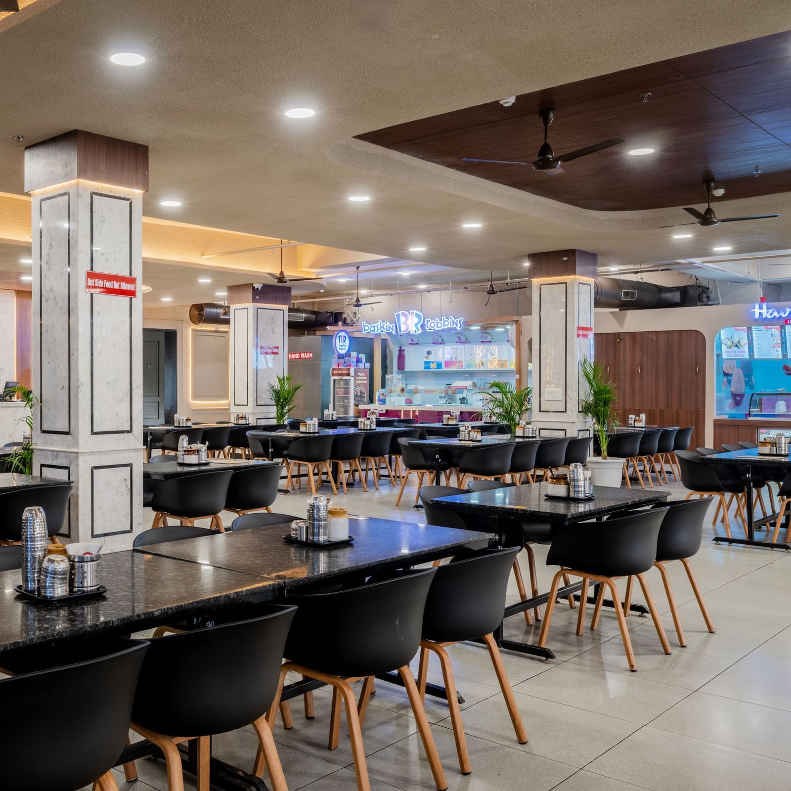 Modern restaurant with neatly arranged seating and elegant ceiling lights at Hotel Highway King, Neemrana.