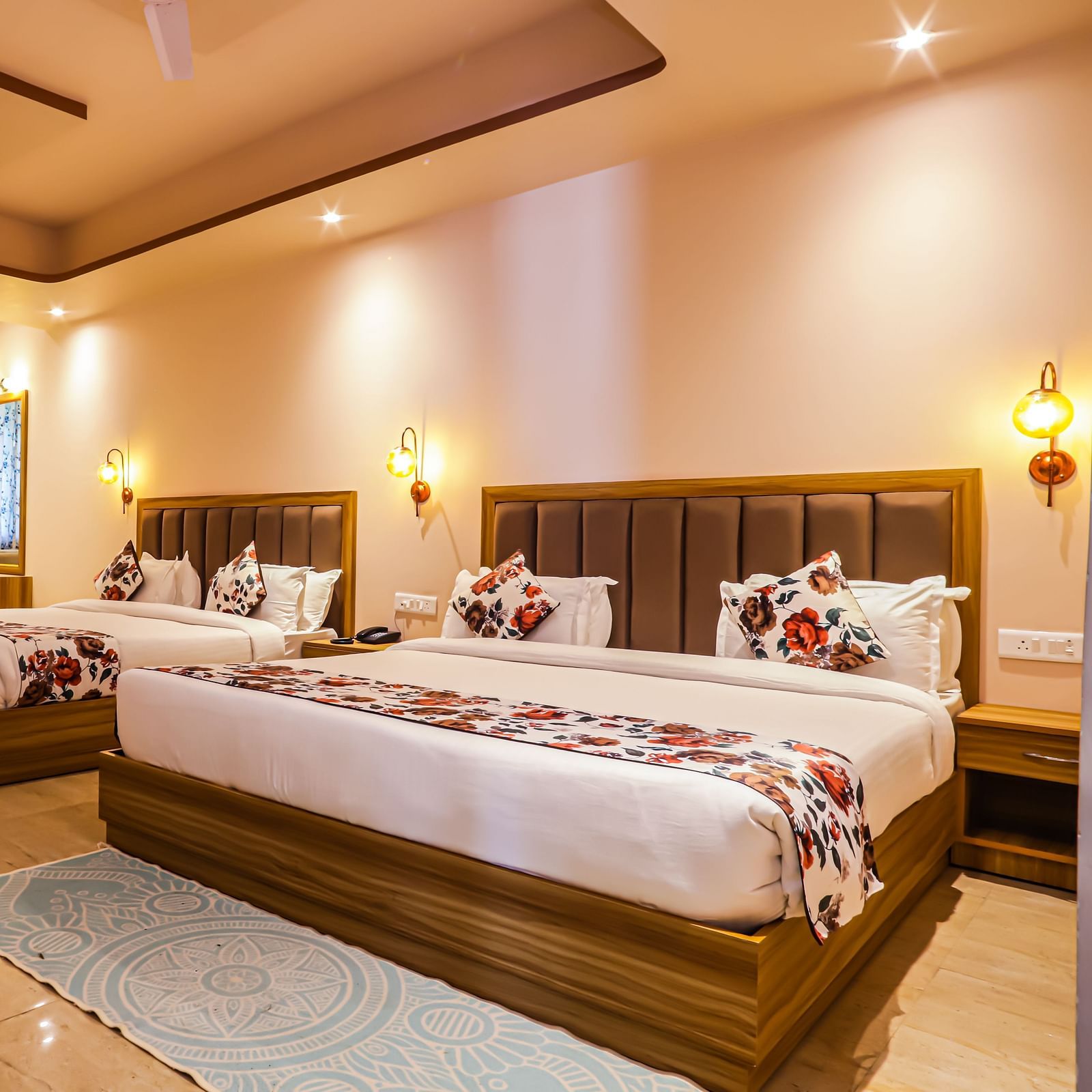 Side of a well lit room with two beds, seating area and ceiling fans - Vedikant Resorts The Mallard Corbett.