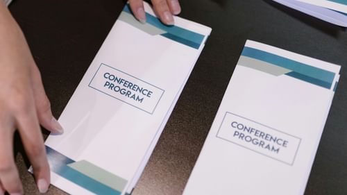 The image shows a person organising a stack of brochures or pamphlets.