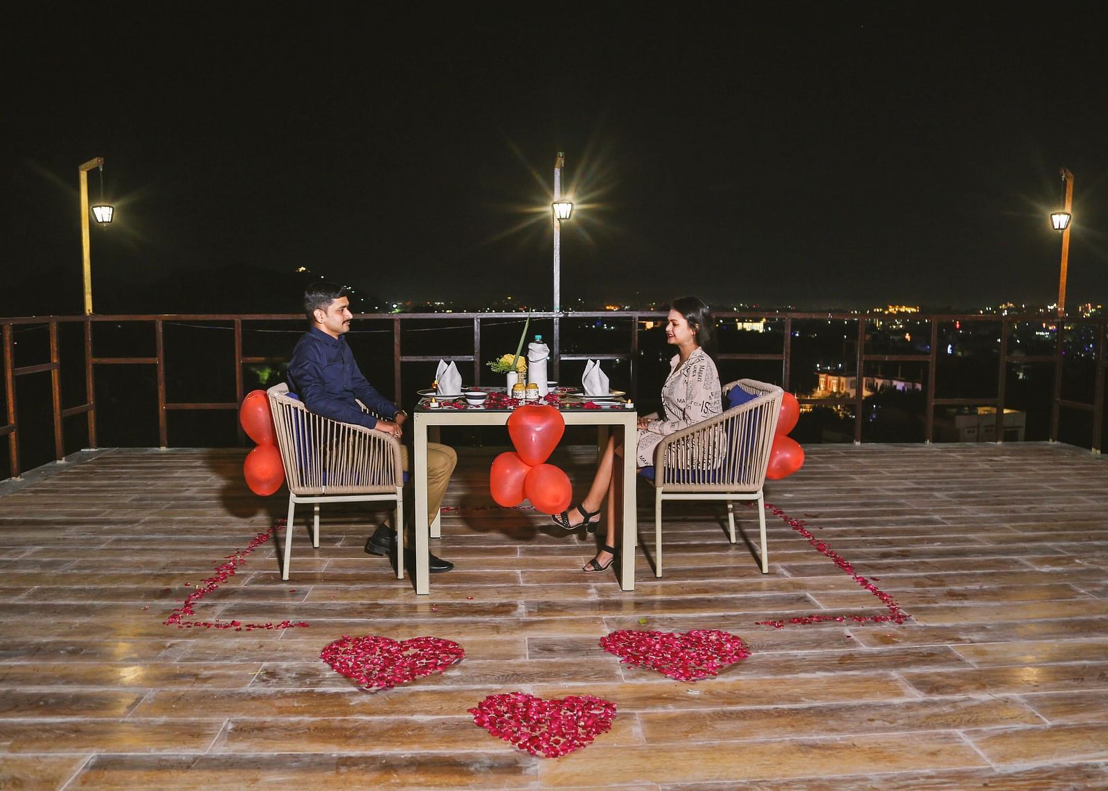 A couple dining outdoor at night with a candlelit table.