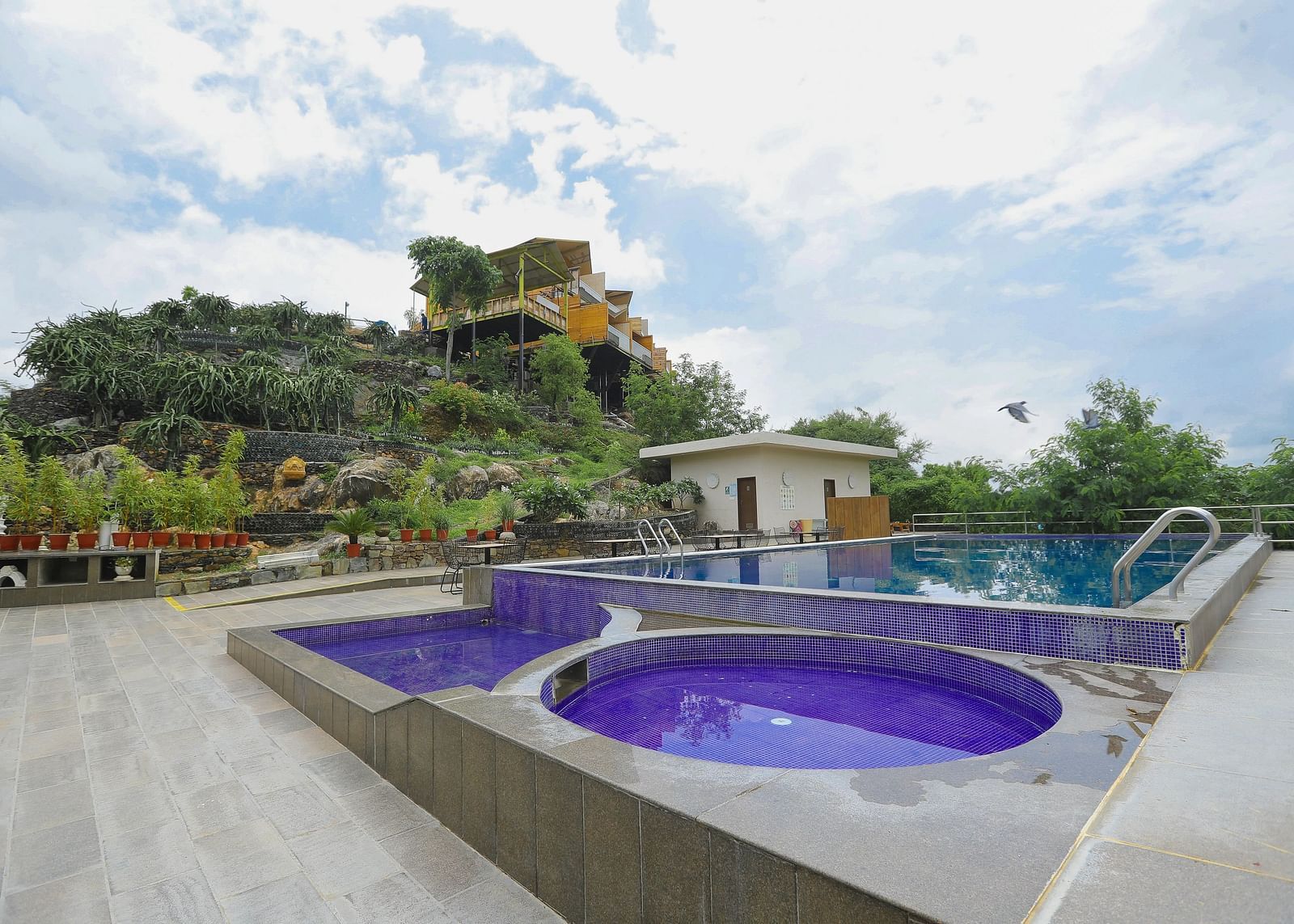 A resort pool area with purple shade pools within a stone architecture.