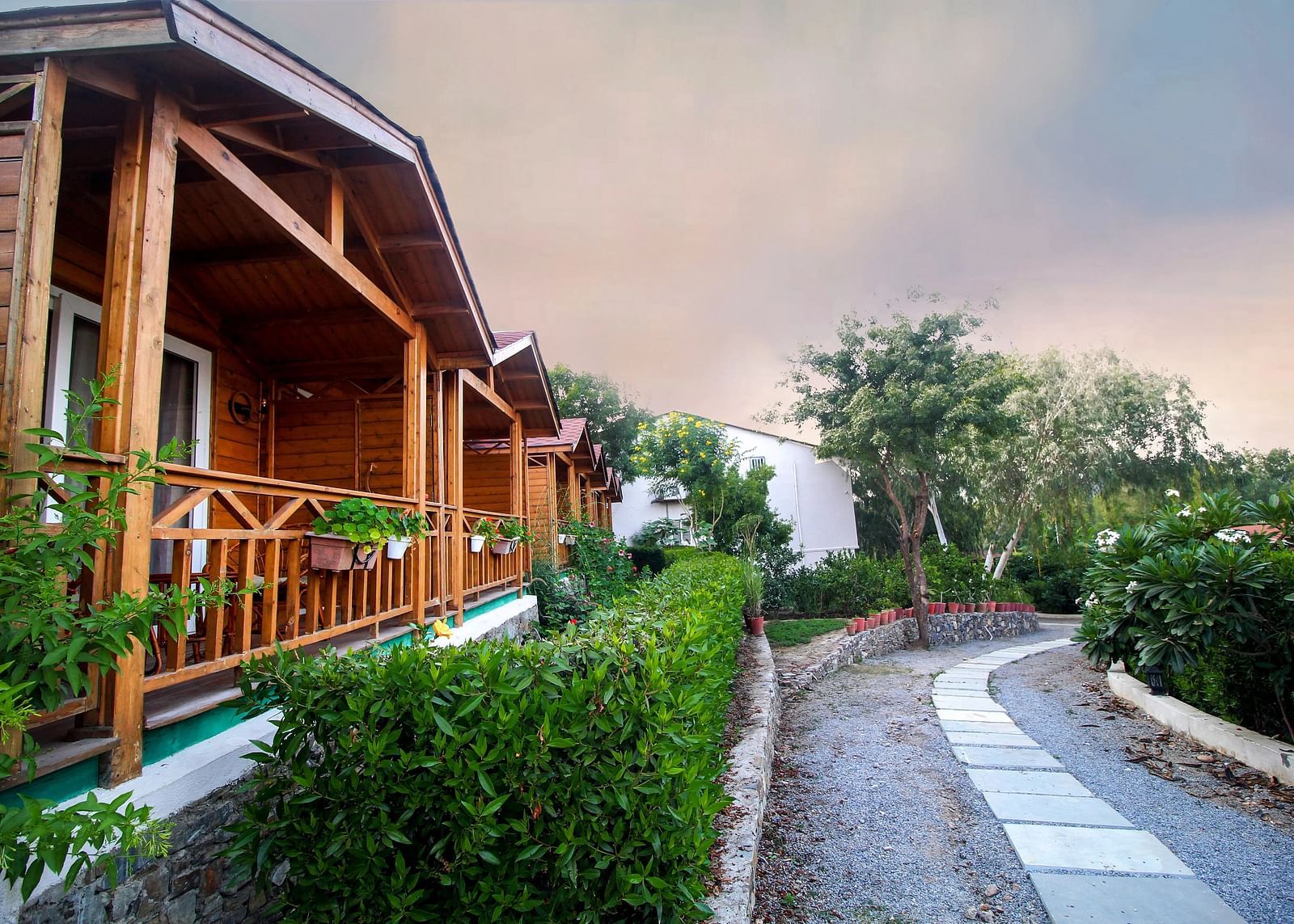 Wooden cabins with green trim along a paved path.