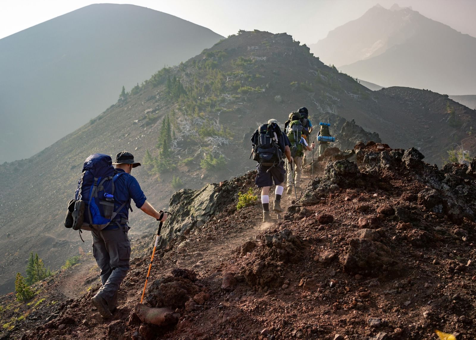 Hikers trekking along a rugged mountain path under a misty sky