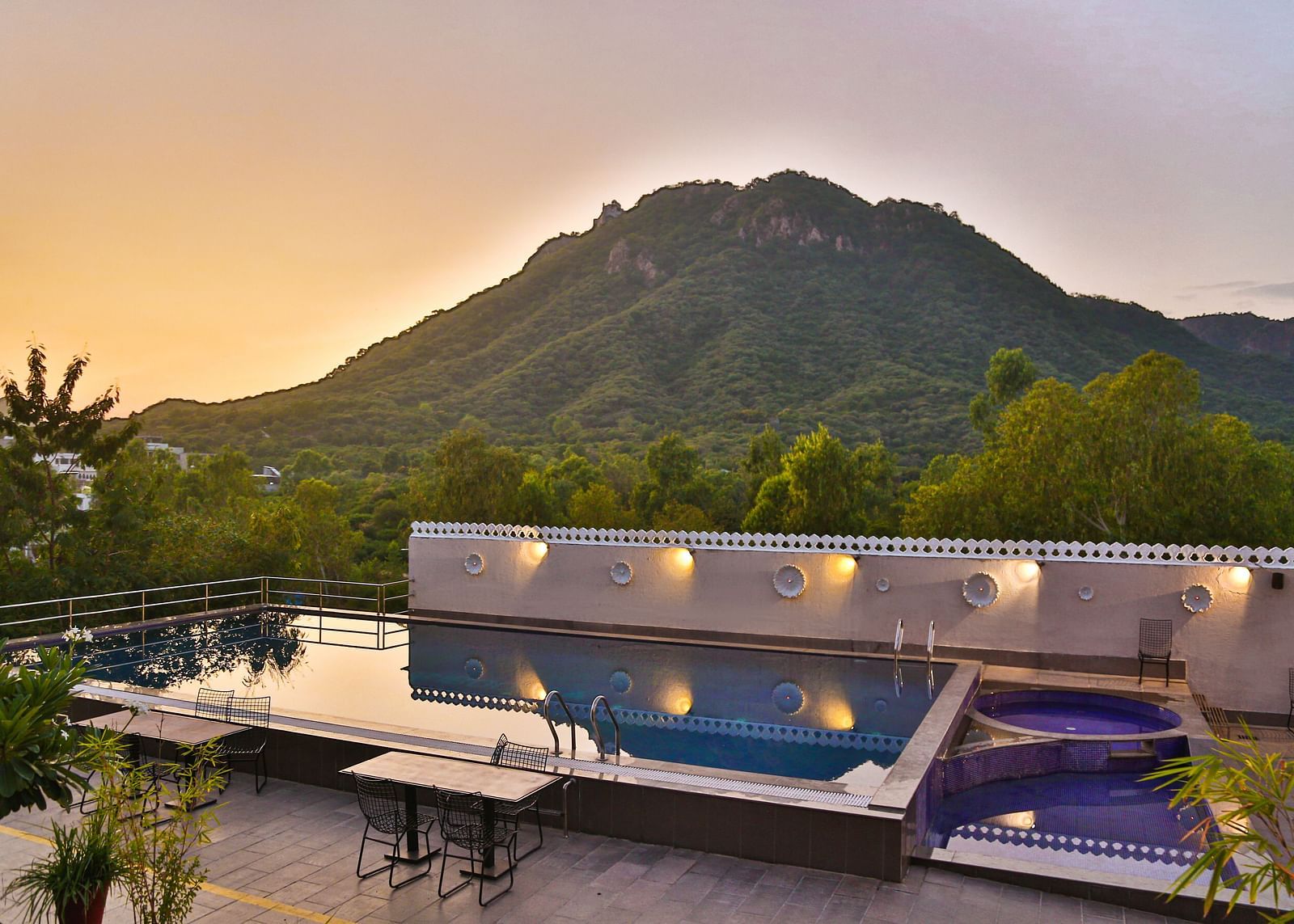 A pool with a view of mountains. - Bamboo Saa Resort & Spa, Udaipur