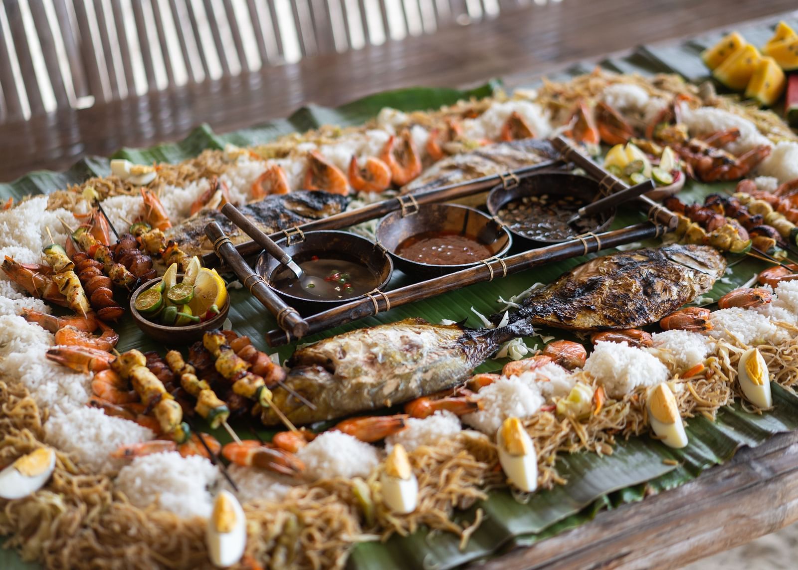 Tabletop grilled seafood and vegetable feast with shells and skewers at Flower Island Resort.