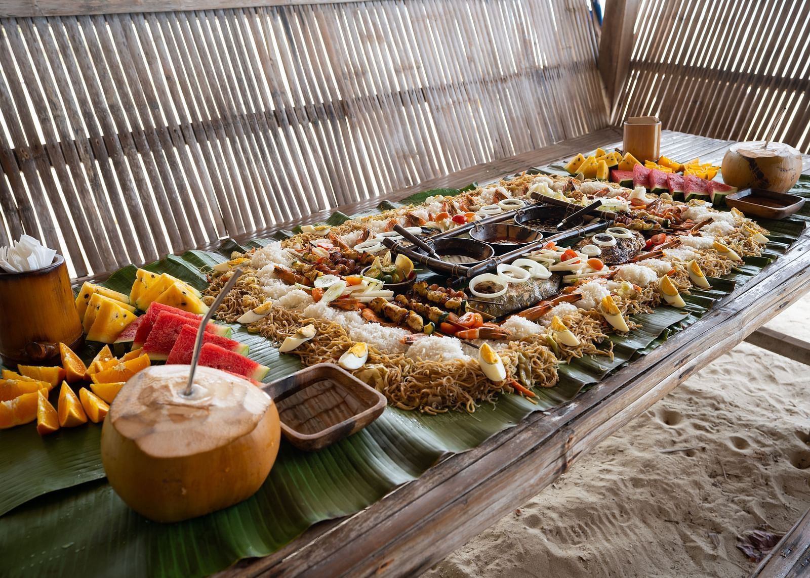 Spread of fruits, rice, tender coconut and local dishes arranged on a bamboo table at Flower Island Resort.
