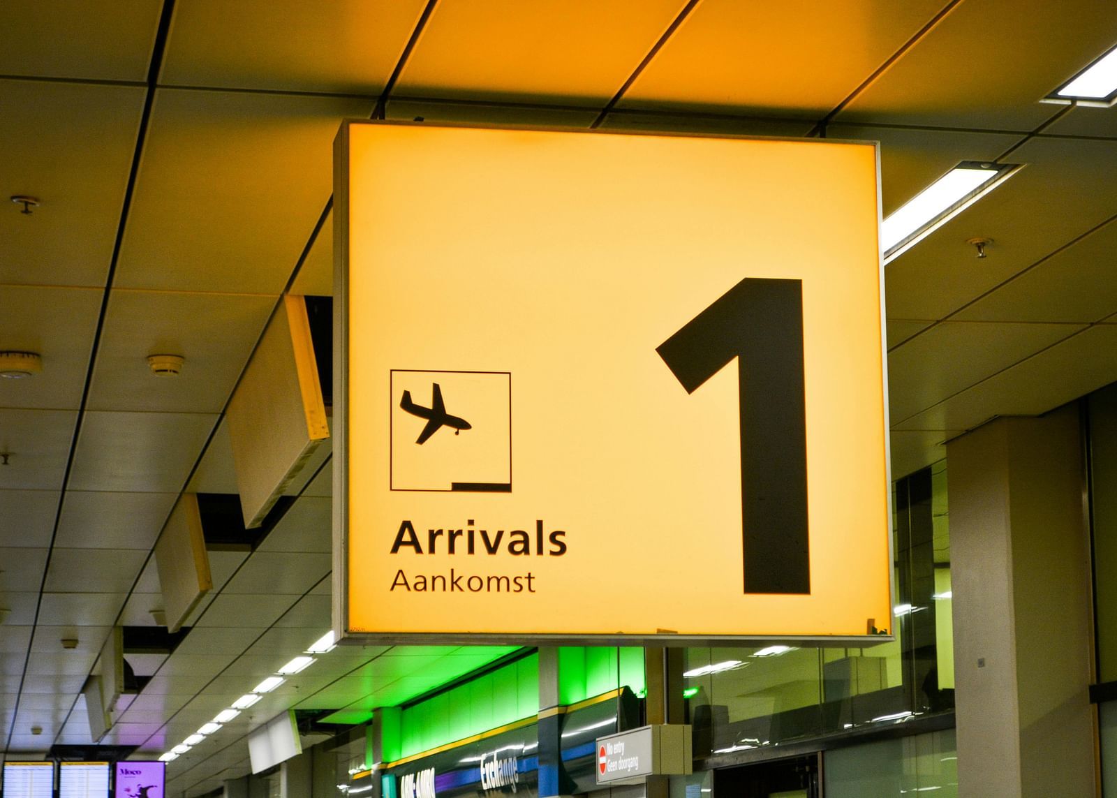 image featuring a signage hanging from the ceiling denoting arrivals at an airport