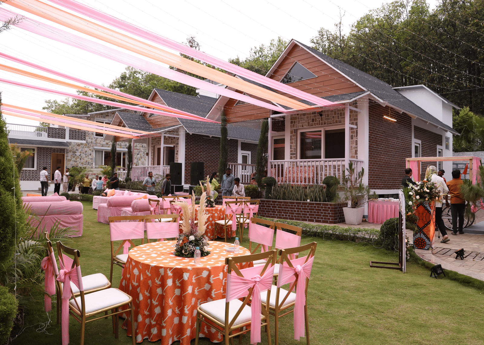 An outdoor event setup with pink and orange drapes, round tables, and chairs - Megha Resort & Villas, Dehradun