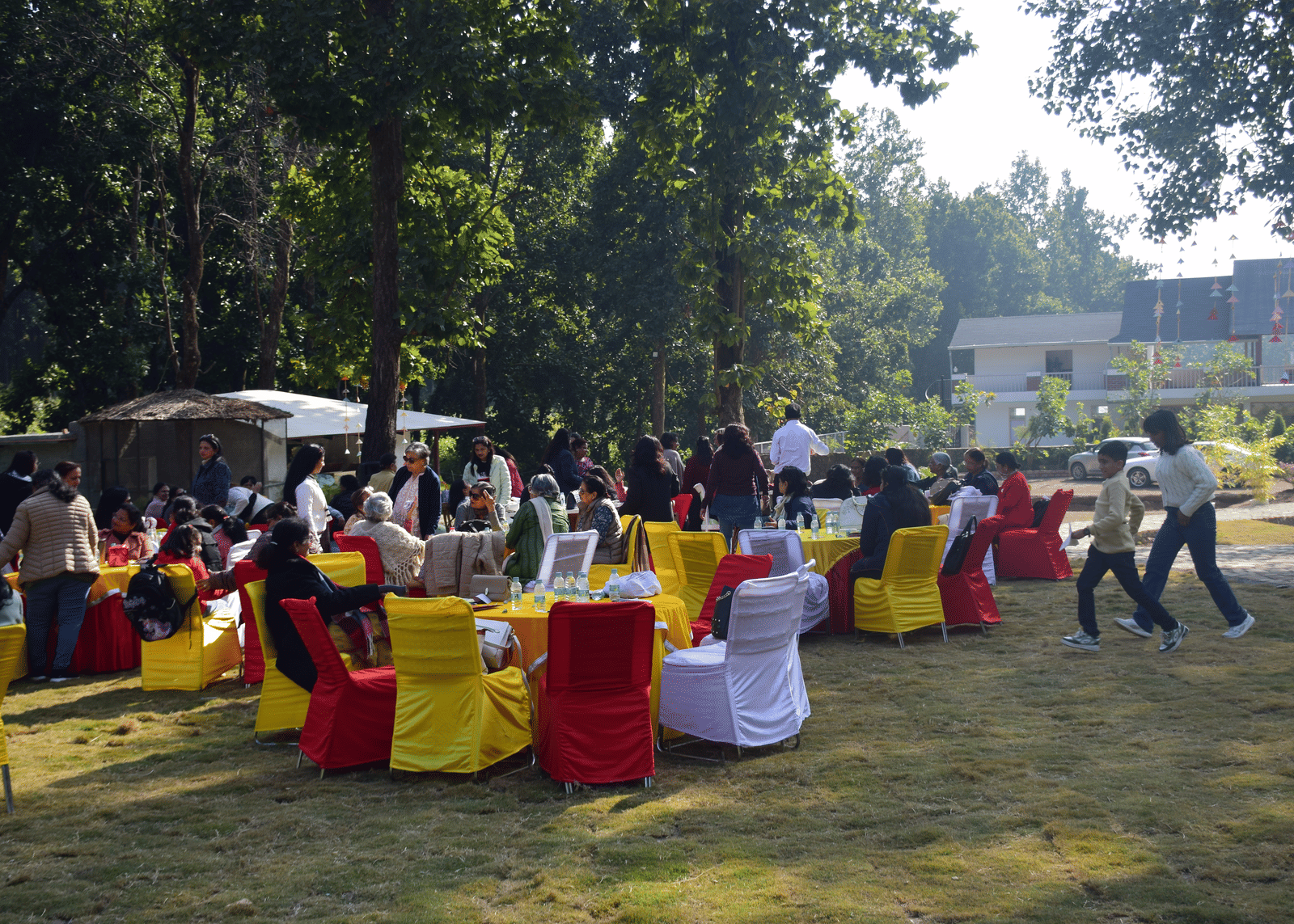 A group of people seated on colourful chairs at an outdoor gathering on a lawn - Megha Resort & Villas, Dehradun