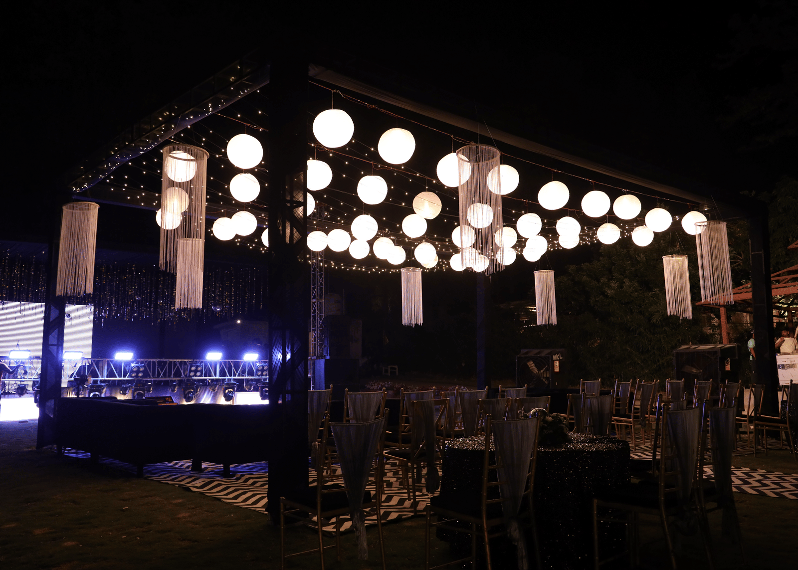 An outdoor evening event with dining tables beneath a ceiling of large, glowing, paper lanterns - Megha Resort & Villas, Dehradun