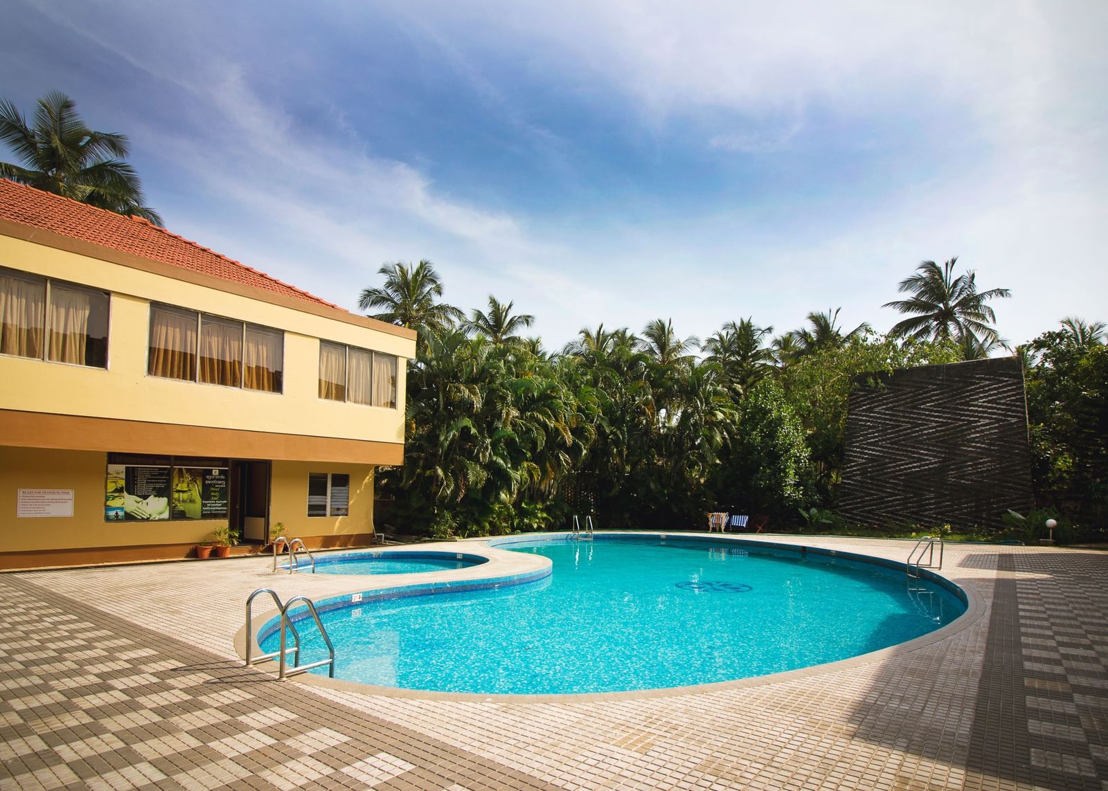 Outdoor swimming pool at Paradise Isle Beach Resort surrounded by palm trees and resort buildings.