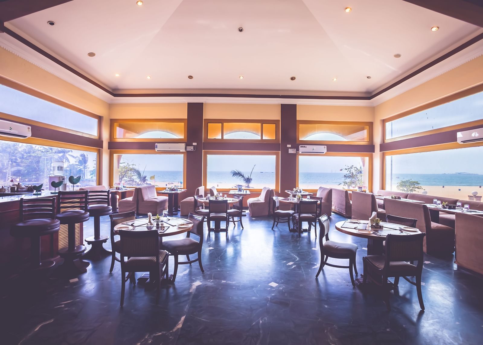 Interiors of a restaurant at Paradise Isle Beach Resort, Udupi with open-air seating arrangement and views of the ocean