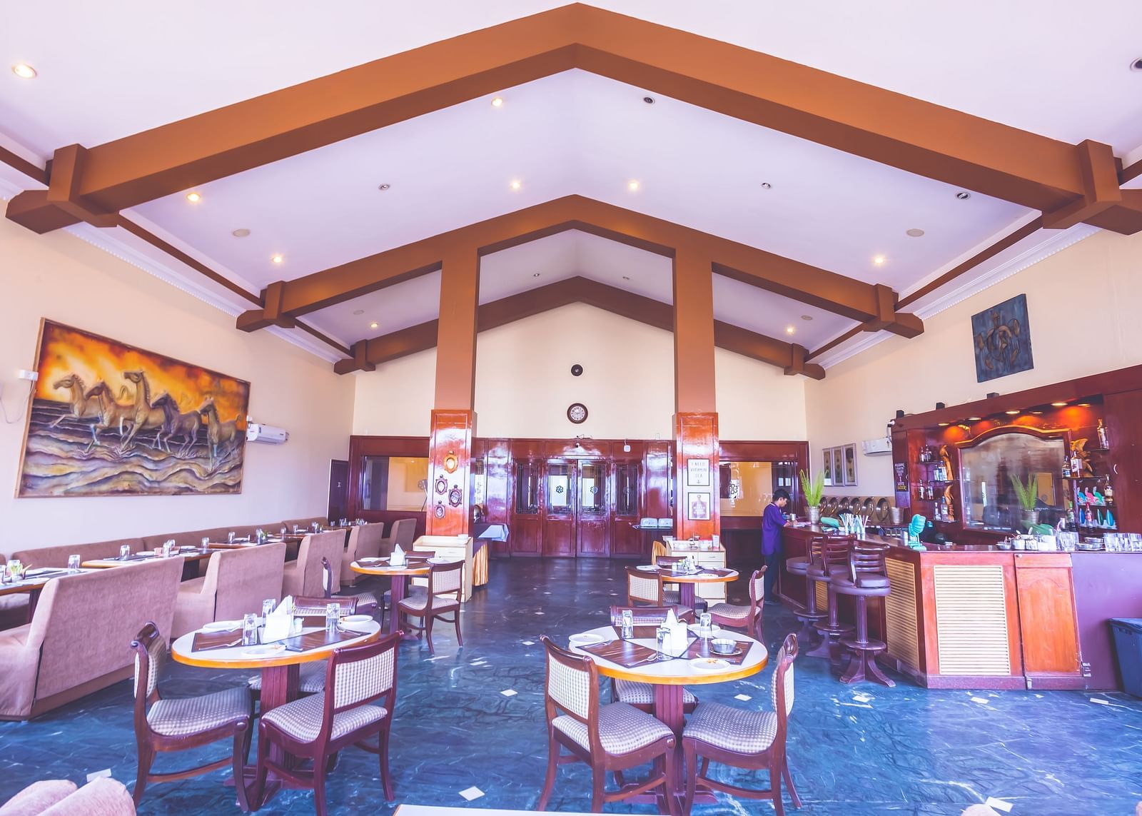 Interiors of a restaurant at Paradise Isle Beach Resort, Udupi with seating arrangement and wooden beams
