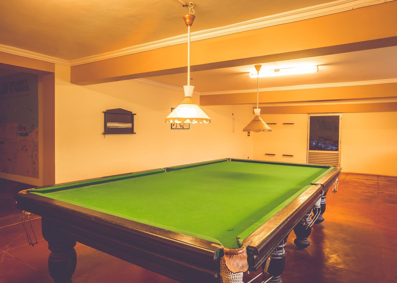 A view of a snooker table lit up by warm lights in the gaming room at Paradise Isle Beach Resort, Udupi