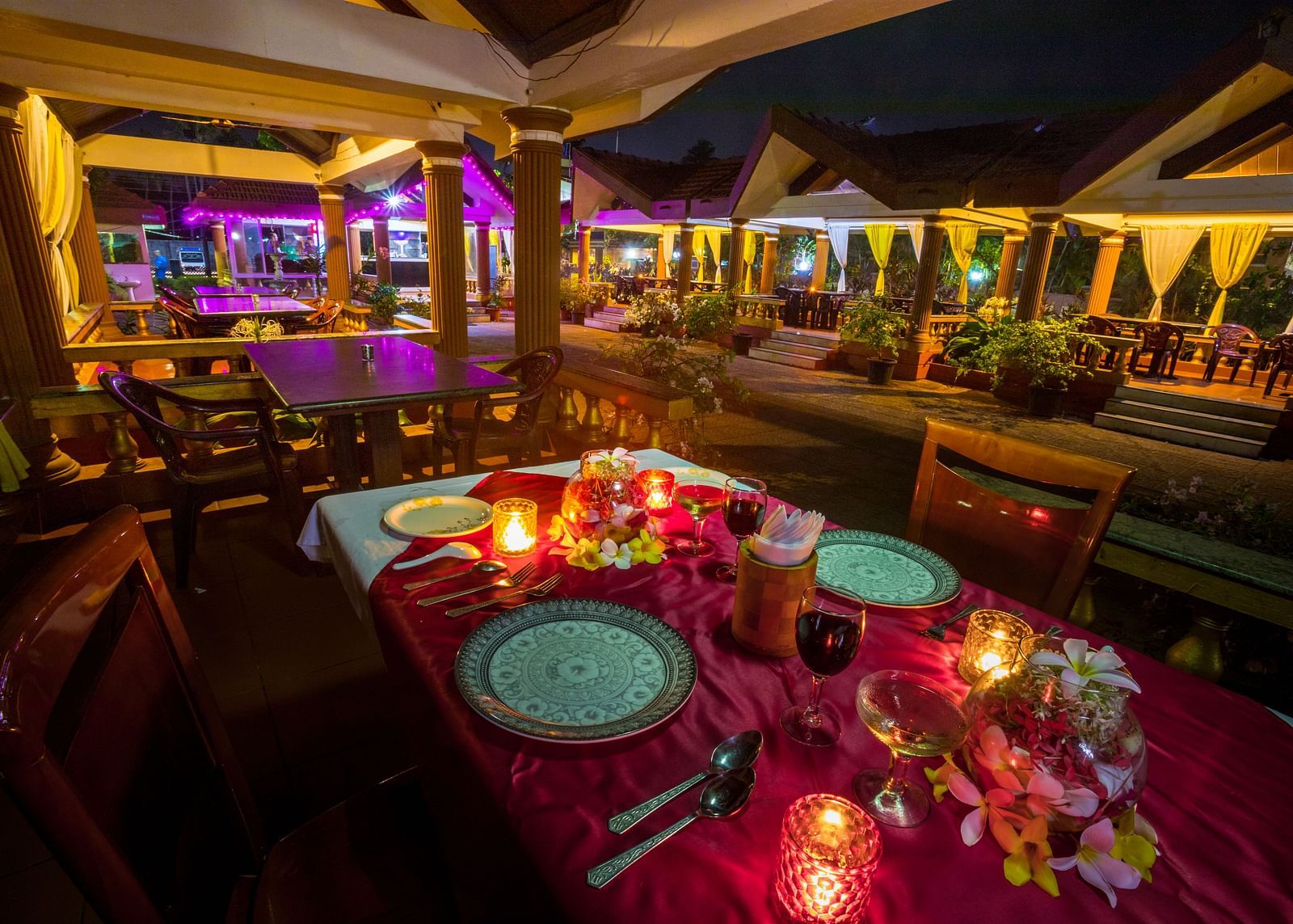 A candle light dining arrangement at Paradise Isle Beach Resort, Udupi with the cottages in the backdrop