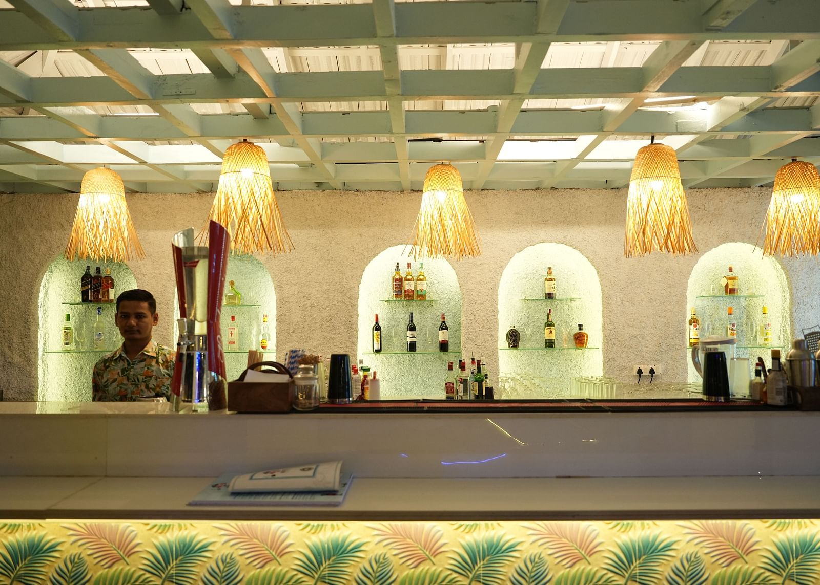 A bar counter in a restaurant at Paradise Isle Beach Resort, Udupi with decorative lights hanging over it