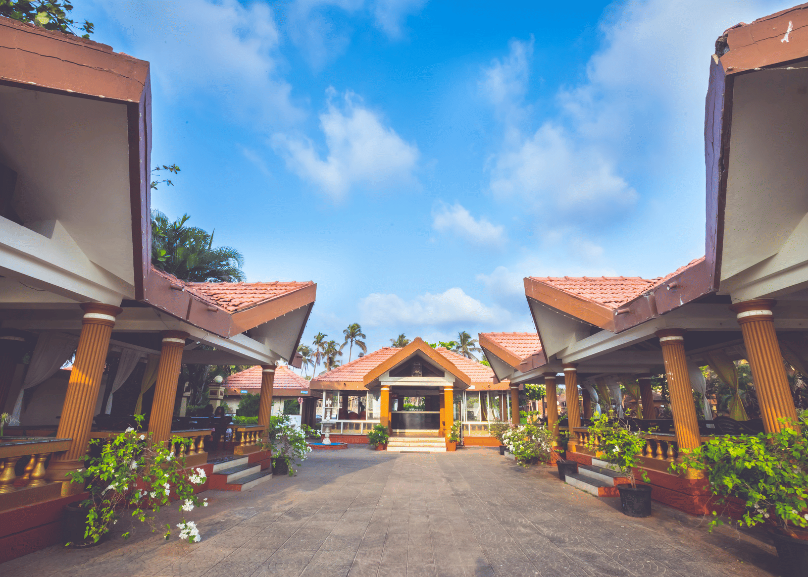 A bright, wide-angle shot of Paradise Isle Beach Resort's entrance, featuring two identical covered walkways leading to a central building.
