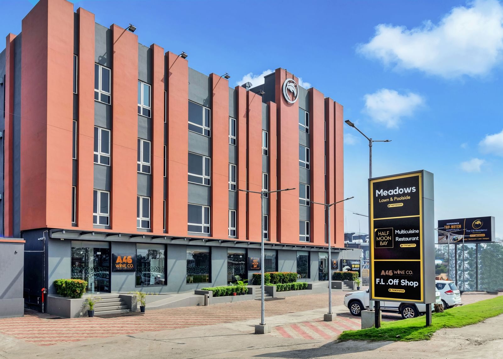 A modern, multi-story hotel building with orange and grey facade under a blue sky with scattered clouds  | The Citi Residenci Hotel Banskopa
