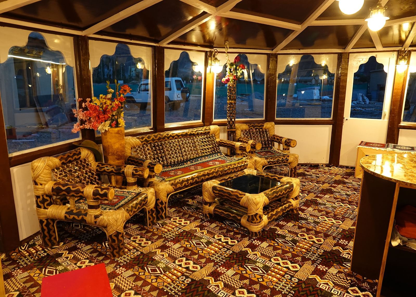 An interior featuring a wooden structure and large arched windows offering outdoor views at White Sands Resort, Ladakh.