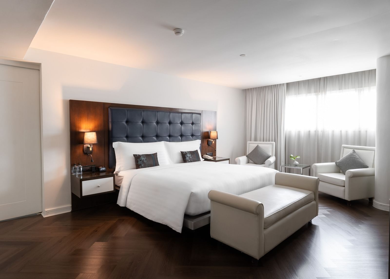 An overview of a double bed with lamps next to the bed inside one of the rooms - Night Hotel Bangkok.