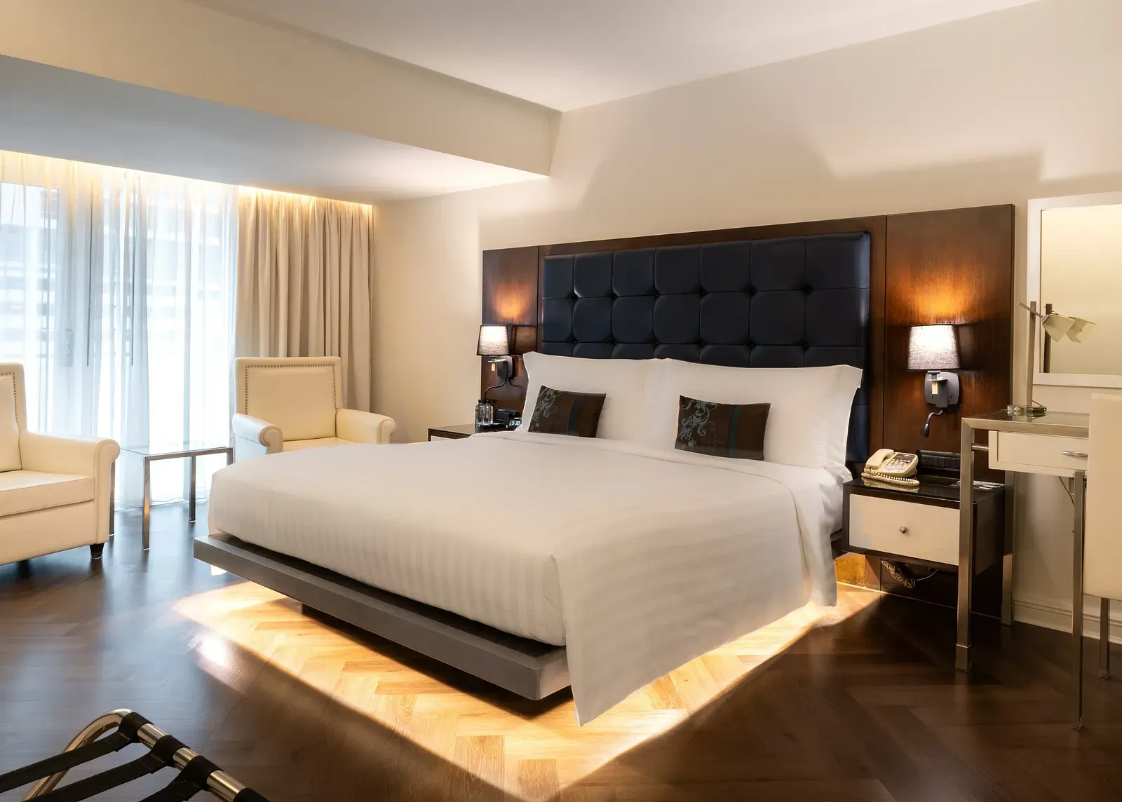 Luxury suite with platform bed, under-bed lighting, and lounge chair at Night Hotel Bangkok.