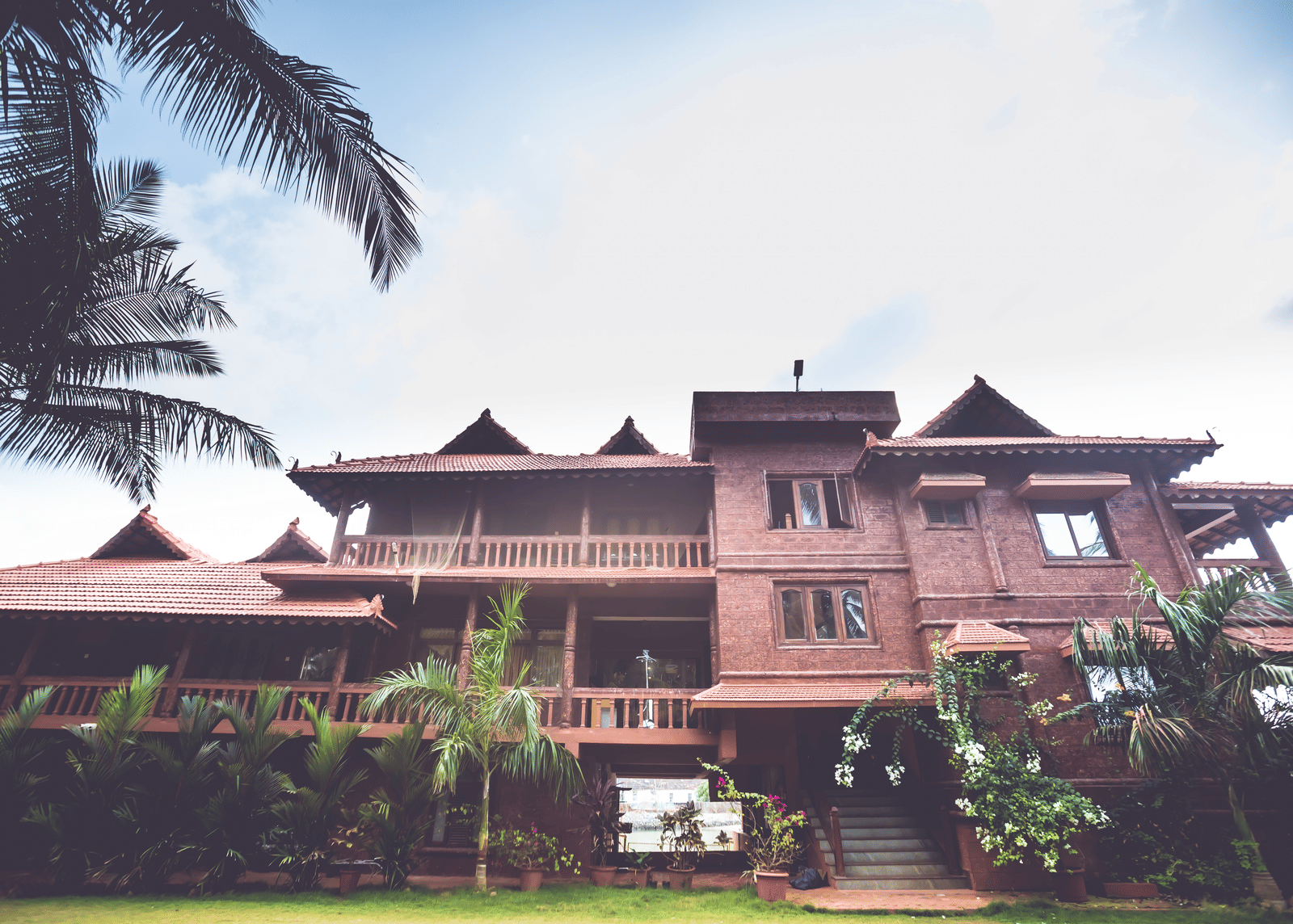 Paradise Lagoon Resort's facade with red-tiled roof, surrounded by palm trees and a driveway.
