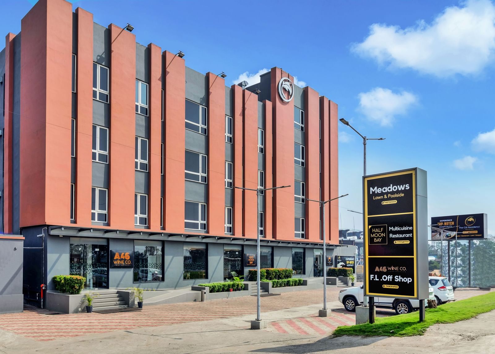 A modern, multi-story hotel building with orange and grey facade under a blue sky with scattered clouds  | The Citi Residenci Hotel Banskopa