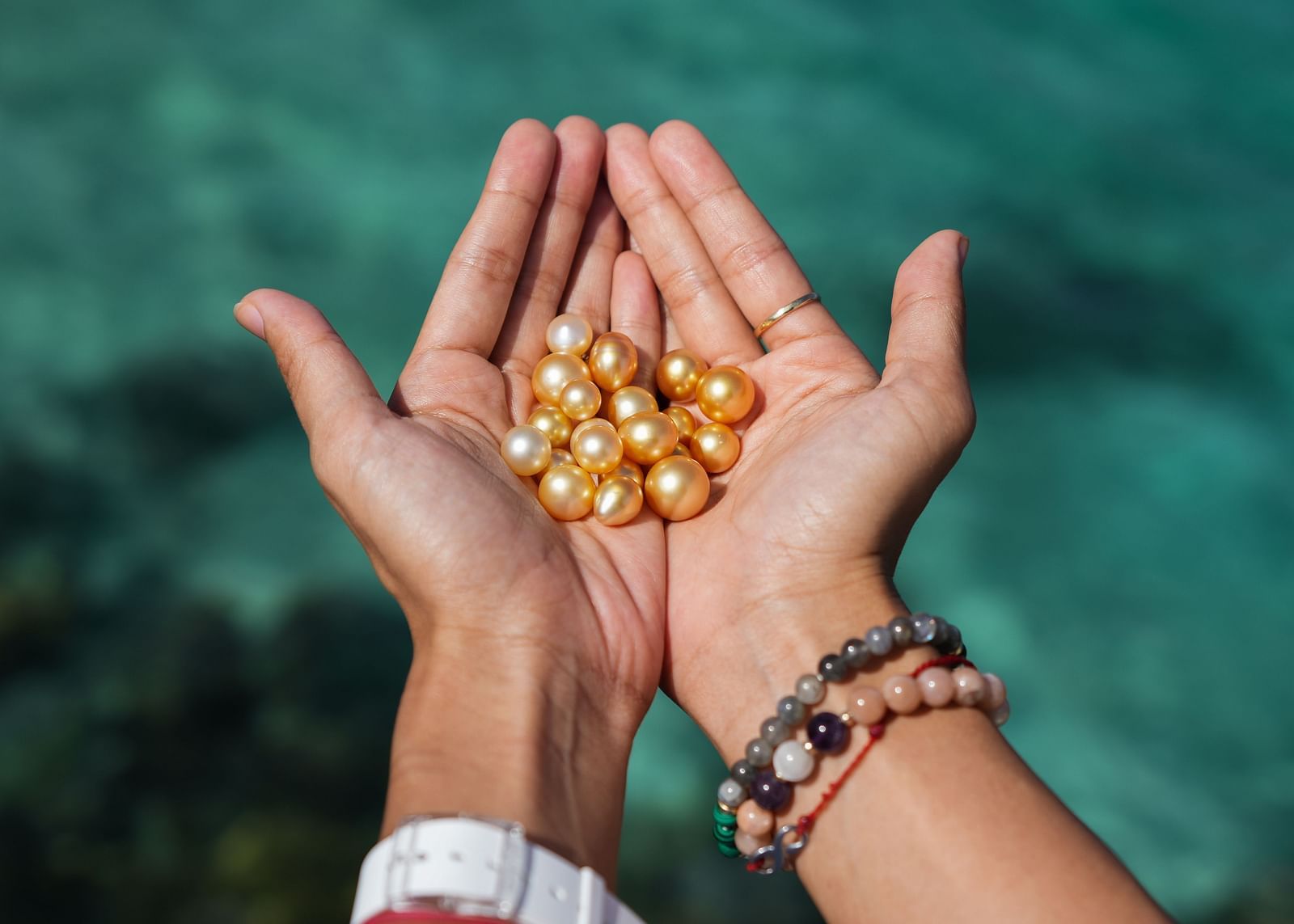 Hands holding a collection of yellow pearls at Flower Island Resort.