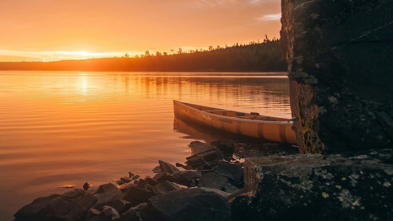 Golden sunset reflecting on calm lake waters with stone structure creating serene evening atmosphere