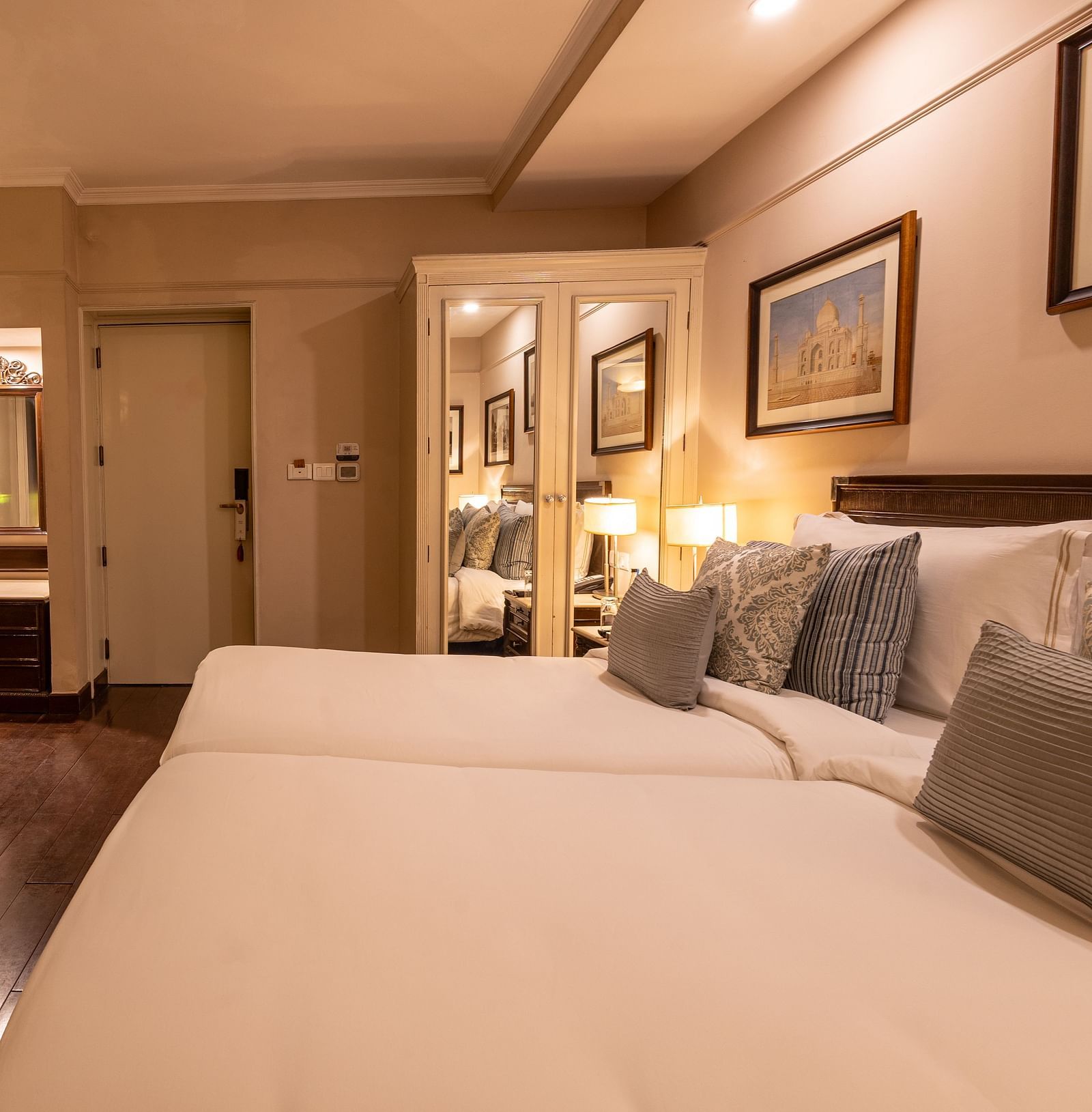 Side view of the Superior Twin Bed Room at The Claridges New Delhi, showcasing twin beds, a wall-mounted TV, and bedside lamps
