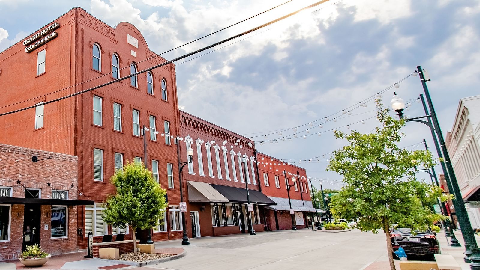 A street view of a  brick building with large windows and storefronts.- The Grand Hotel & Ballroom, McKinney