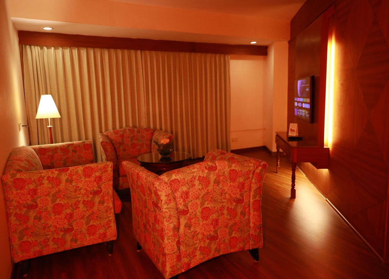 A living room with a plush sofa, armchairs, and a coffee table, decorated with warm lighting at Accord Highland Ooty.