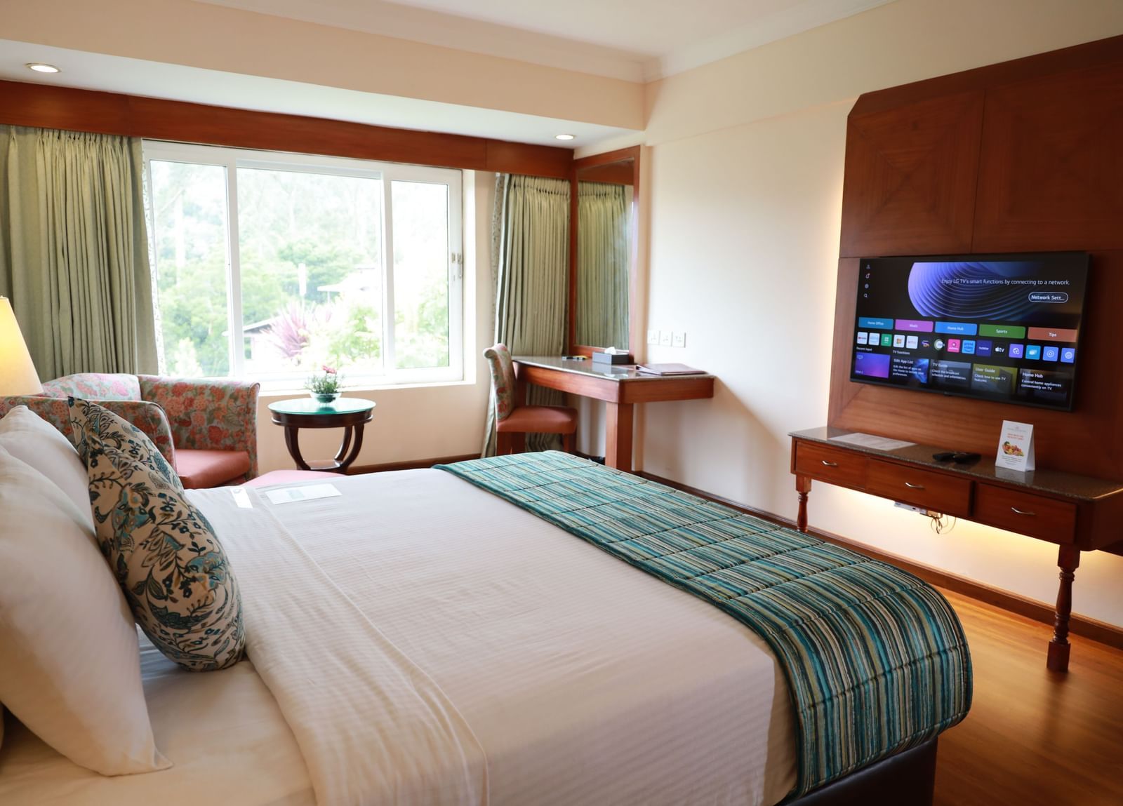 Superior Room at Accord Highland Ooty room, featuring a king-sized bed, a window view, and a wall-mounted TV.
