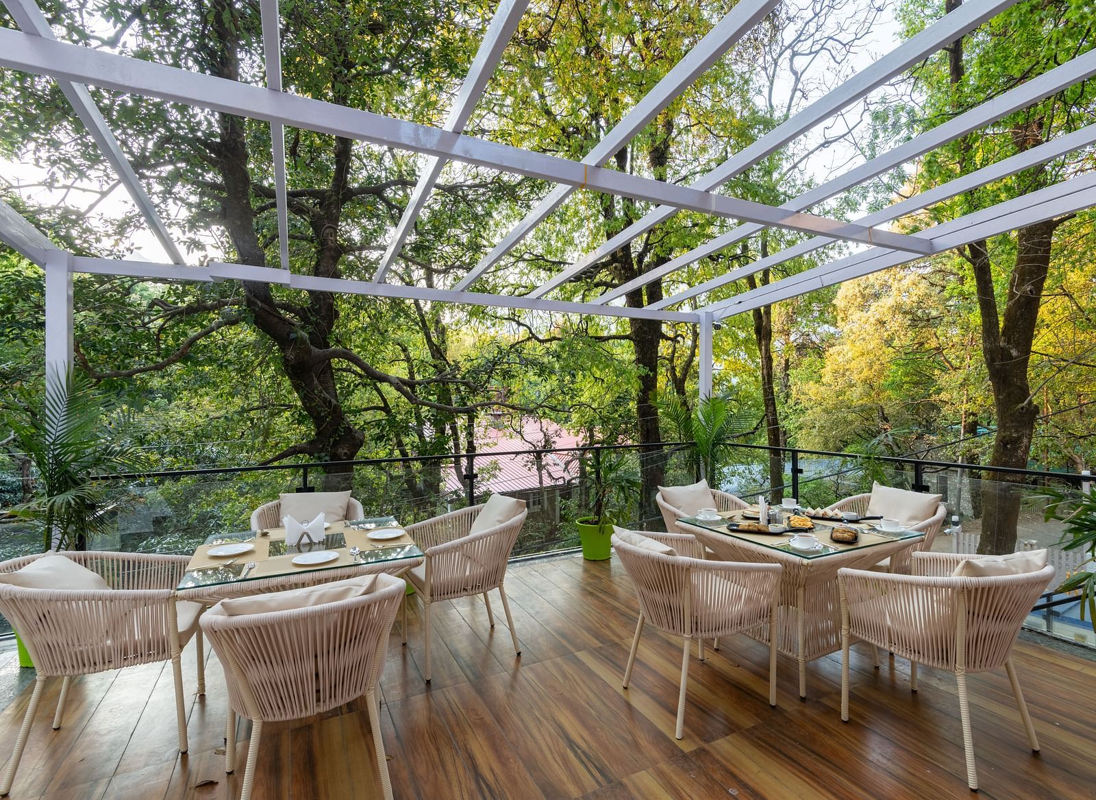 The deck at DLS The Emerald, Nainital with chairs and tables with the background of trees and greenery