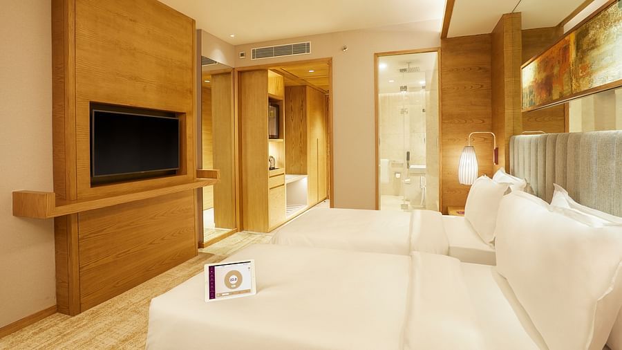 Side view of Premier Rooms featuring a wall-mounted TV and a bedside light in the corner at The Residency Towers Chennai
