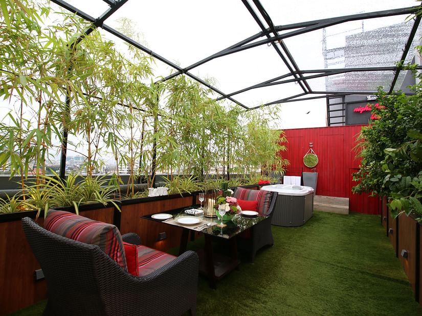 An image of a cafe featuring chairs and tables surrounded by plants and glass ceilings  | Theory9 - Premium Service Apartments, Bandra