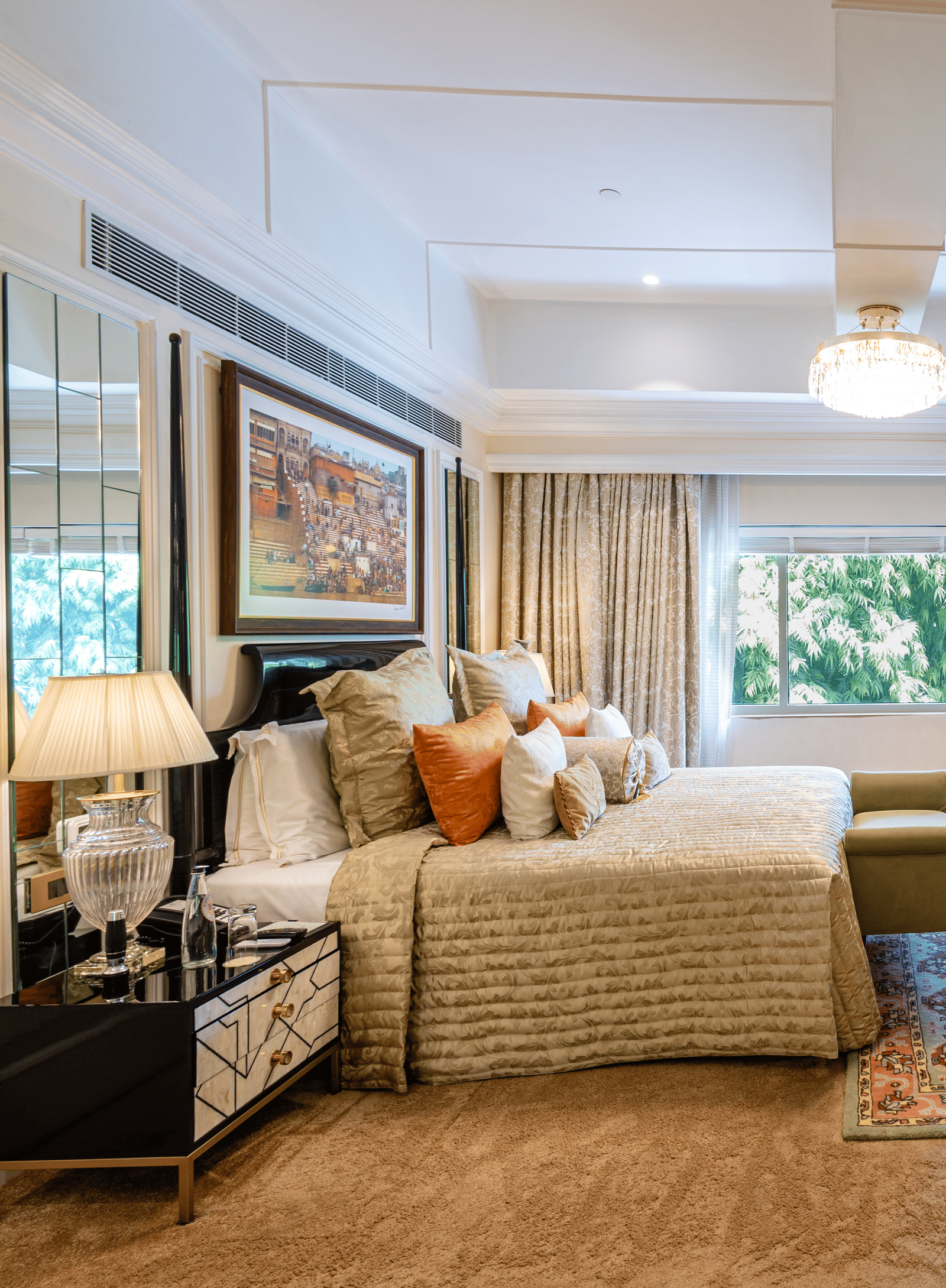 Presidential Suite bedroom featuring a sofa, armchair, coffee table, television, floor lamp, and large windows overlooking greenery at The Claridges New Delhi.