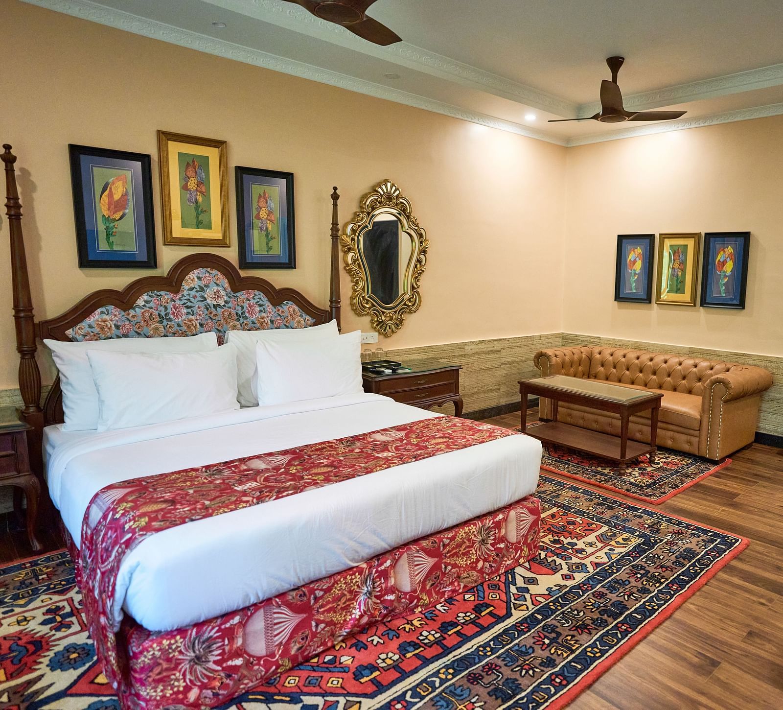 A spacious room with a large bed on one side and cushioned seating furniture on the other, adorned with wall-mounted frames for decoration at Mayfair Manor, Alibag