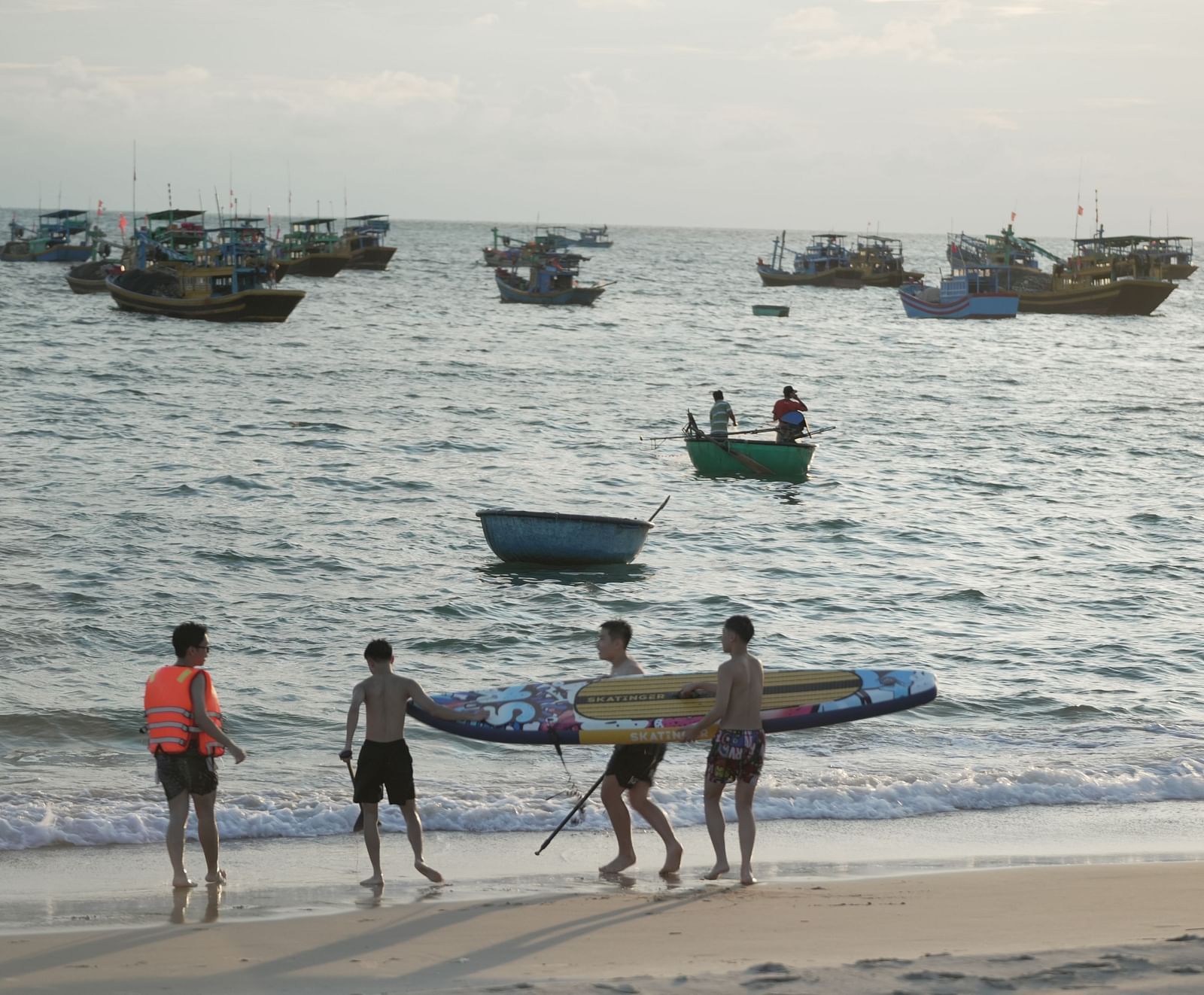 People engaging in water activities such as paddleboarding and kayaking on the beach at WoCAL Retreat Ke Ga.