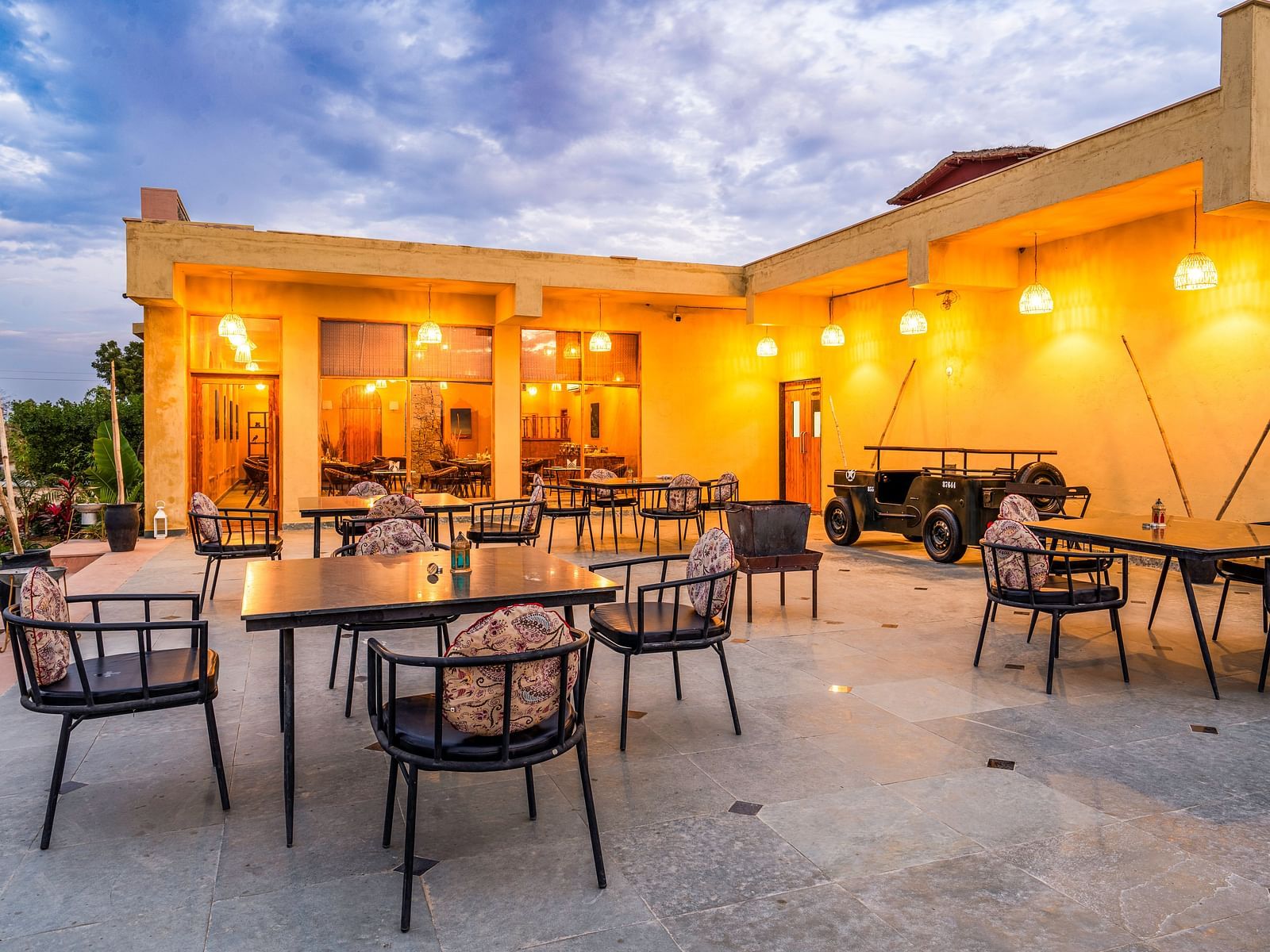 An image of rosettes restaurant featuring several lamps hanging from the roof and various sets of  tables and chairs are placed both indoor and outdoor at Kurja Jawai