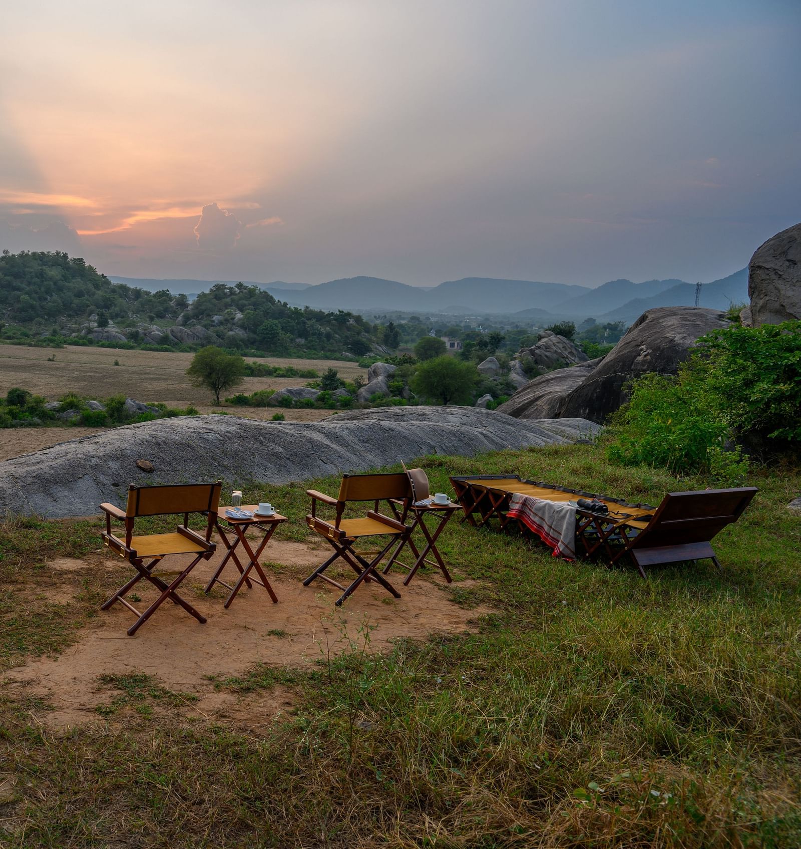 An image of an outdoor seating amidst greenery over viewing the mountains - Utsav Camp Sariska.